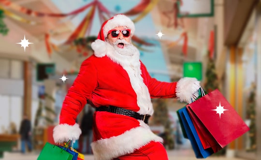 papai noel com roupa vermelha e branca usando óculos escuros e carregando sacolas de compras de natal